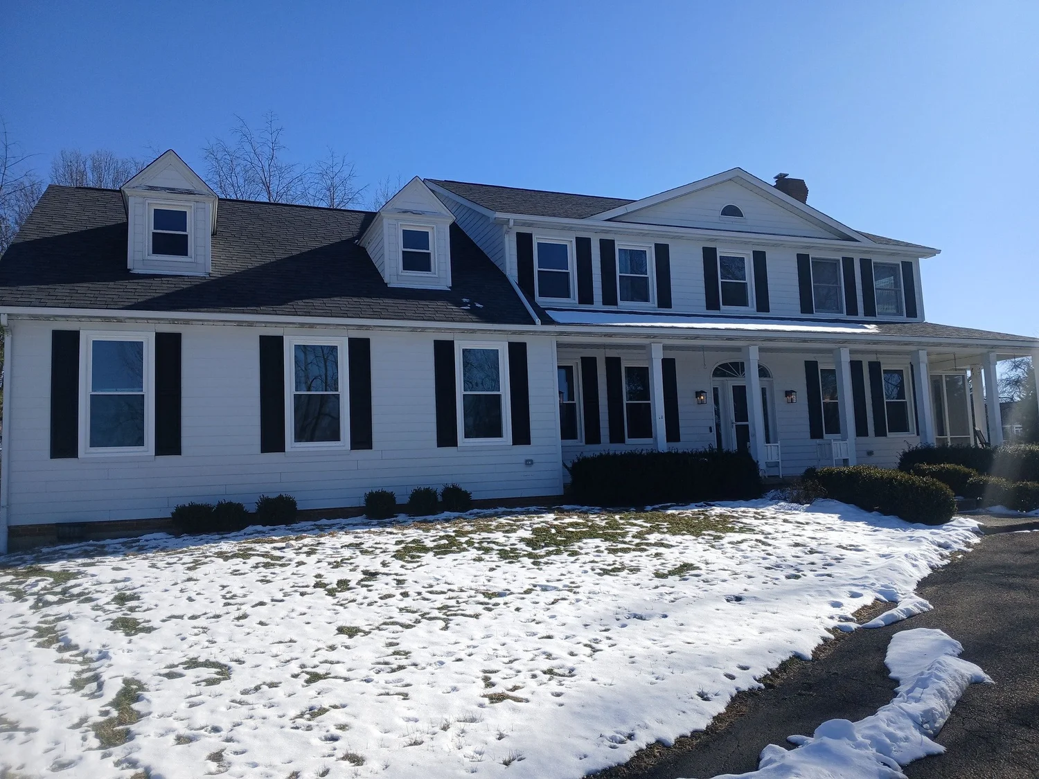 White two-story house with dark shutters and new windows.
