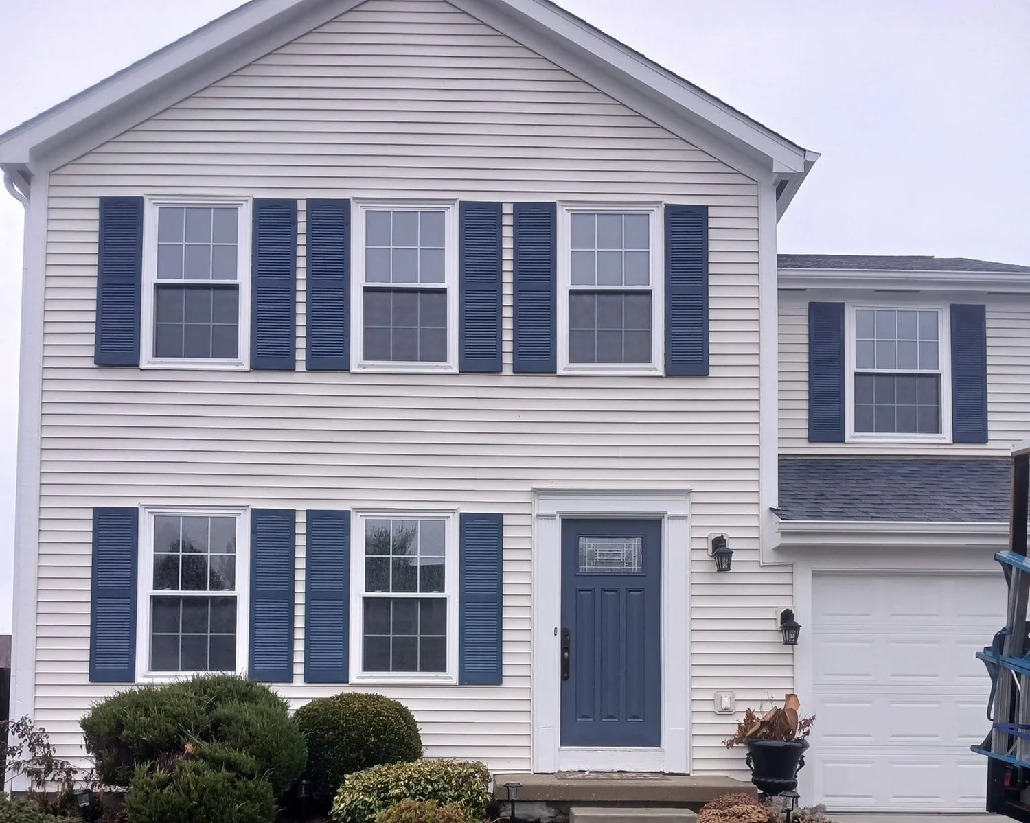 Two-story house with beige siding and energy-efficient windows.